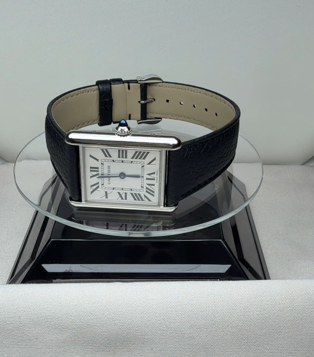 Cartier Tank in size L with a white dial, Roman numerals and a black leather strap, angled view
